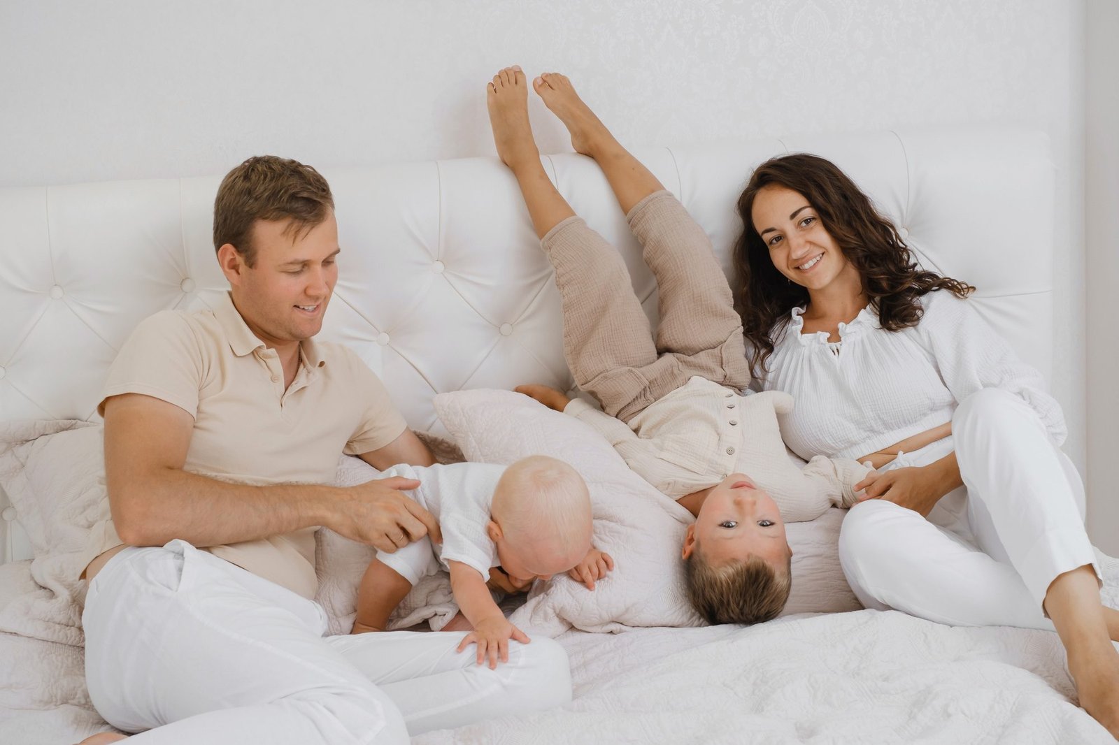 Parents playing with children in bed in a cozy white flat